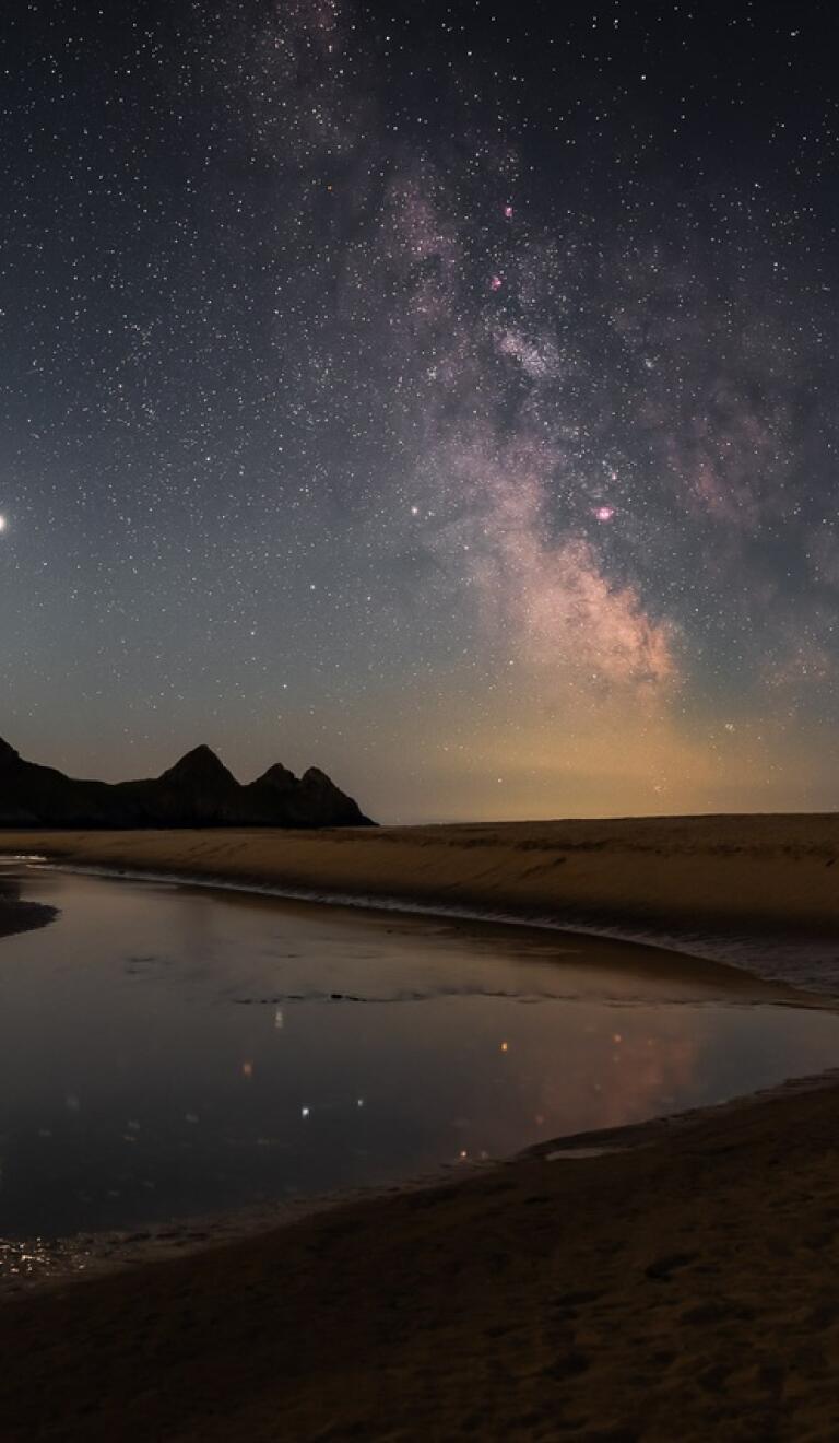 The Milky Way in the night sky highlighting the beach at Three Cliffs Bay, Gower