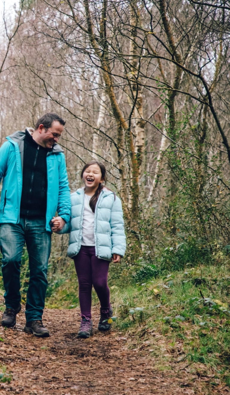 father and daughter walking in forest.