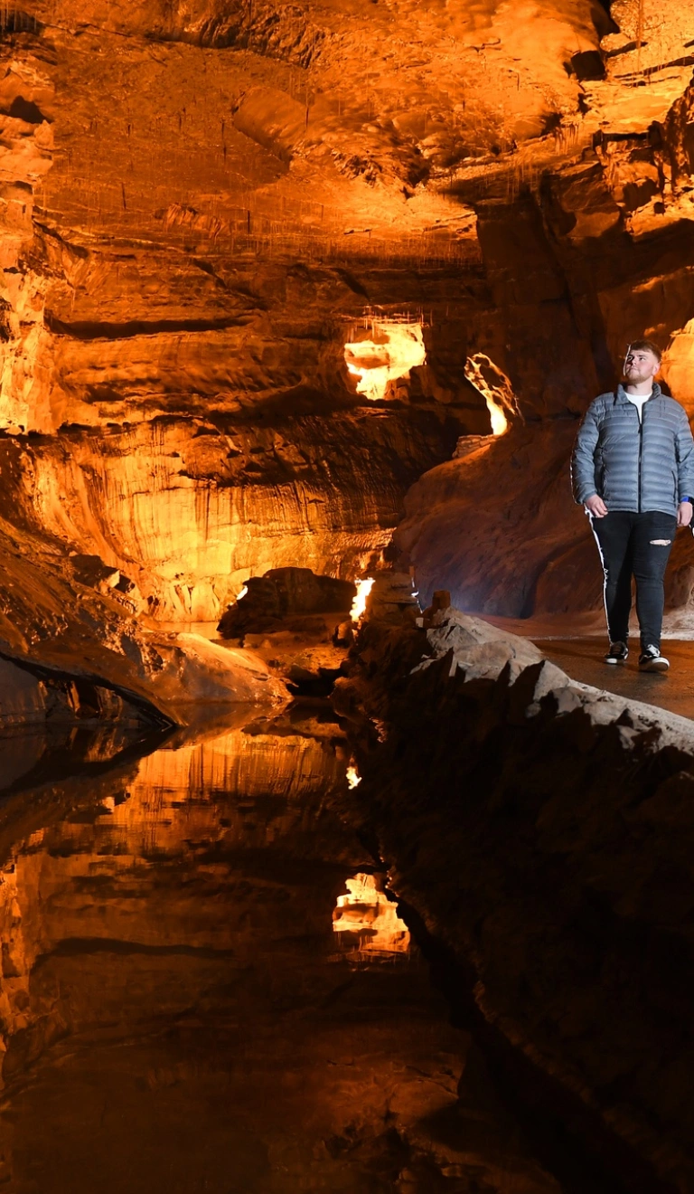 Two people walking along an underground path in a cave.