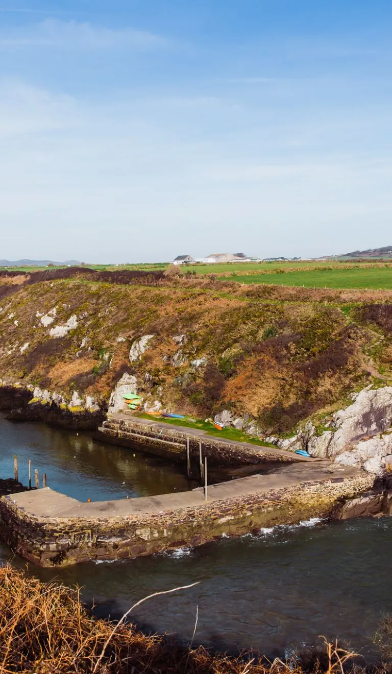 A small harbour surrounded by cliffs with the tide in.