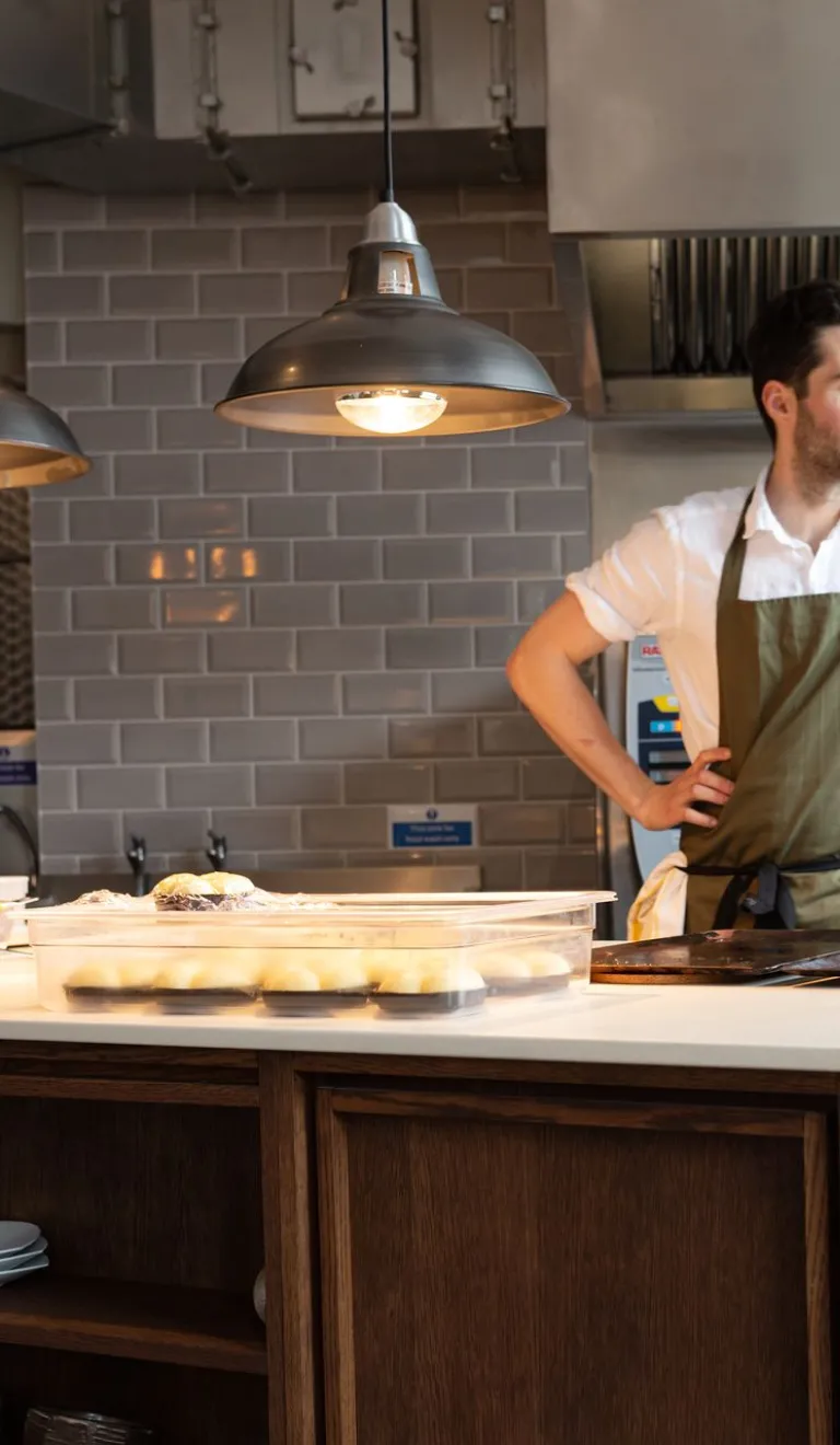 Person preparing food at a kitchen island in a modern restaurant kitchen.