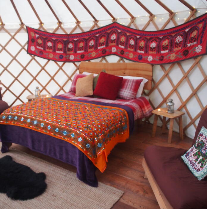 Sleeping area in a luxury yurt with wall hangings.